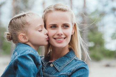 little adorable daughter kissing her blonde mother  clipart
