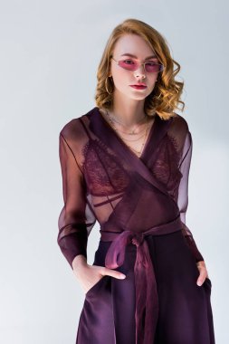 elleri ceplerinde duran ve gri izole kamera bakarak güneş gözlüğü güzel şık kız portresi
