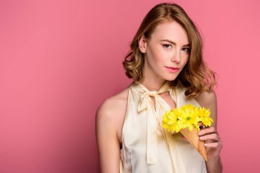 dondurma külahı sarı çiçekler ile tutarak ve pink izole kamera bakarak kız