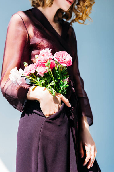 cropped shot of elegant young woman holding tender flowers isolated on grey 