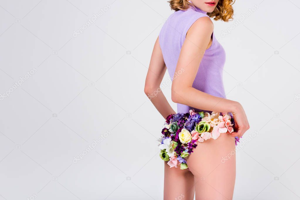 cropped shot of beautiful tender woman in panties made of flowers standing isolated on grey