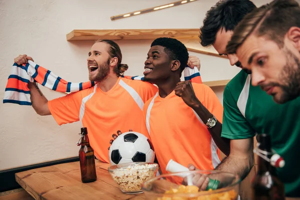 Smiling Multicultural Football Fans Orange Shirts Scarf Celebrating Victory Ball — Stock Photo, Image