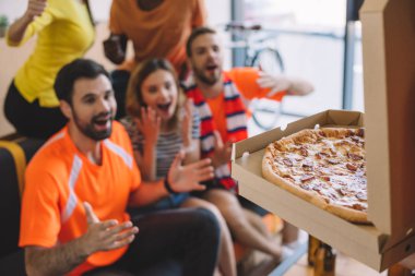 pizza kutusu ve heyecanlı grup evde koltukta oturan arkadaşının fotoğrafını kapatın