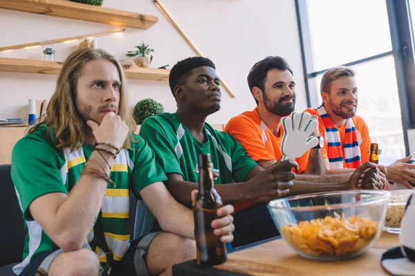 Группа Друзей Мультикультурных Мужчин Зеленых Оранжевых Футболках Смотрящих Футбольный Матч — стоковое фото
