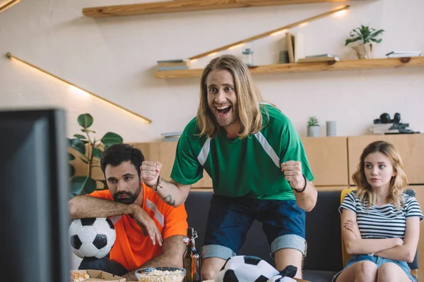 Feliz Joven Verde Ventilador Camiseta Celebrando Mientras Sus Amigos Molestos — Foto de Stock