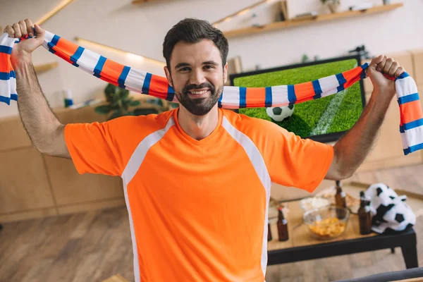 Retrato Joven Camiseta Abanico Naranja Sosteniendo Bufanda Rayas Celebrando Victoria — Foto de Stock