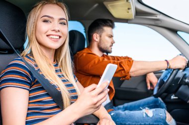 Genç kadın holding smartphone el araba onun erkek arkadaşı gülümseyen 