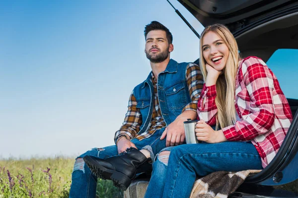 Smiling Woman Coffee Cup Her Boyfriend Sitting Car Trunk Field — Free Stock Photo