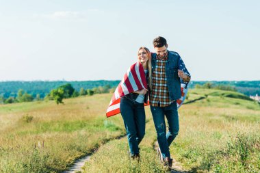 kırsal çayır, bağımsızlık günü kavramı üzerinde Amerikan bayrağı ile mutlu genç çift