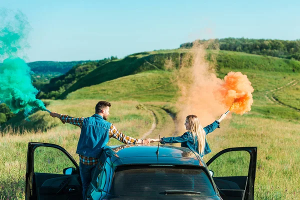 カラフルな爆弾車の上に立って 地方の草原に手を繋いでいるカップルの背面図 — ストック写真