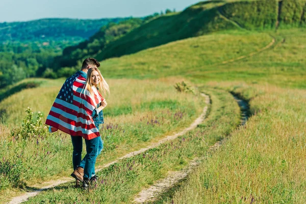 Baksidan Unga Par Med Amerikanska Flaggan Landsbygden Äng Självständighetsdagen Koncept — Stockfoto