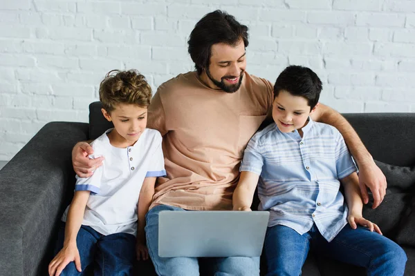 Uomo Sorridente Figli Vicino Utilizzando Computer Portatile Sul Divano Casa — Foto stock gratuita