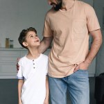 Portrait of smiling boy and father looking at each other at home