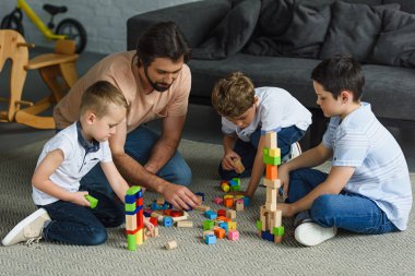 Baba ve ahşap bloklar ile birlikte evde katta oynayan çocuklar