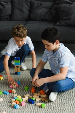 little boys playing with wooden blocks on floor at home clipart