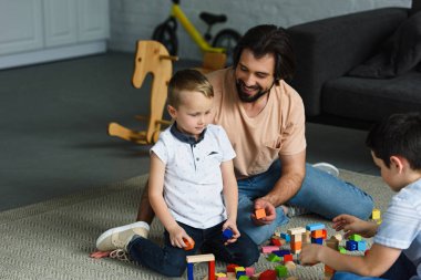 Baba ve ahşap bloklar ile birlikte evde katta oynayan çocuklar