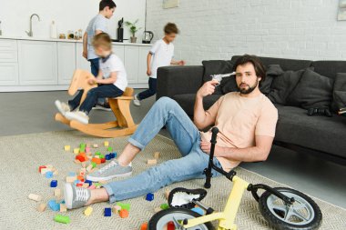 katta ve çocuklar odada iskambil çevrede oturan kafasına oyuncak tabancalı yorgun adam