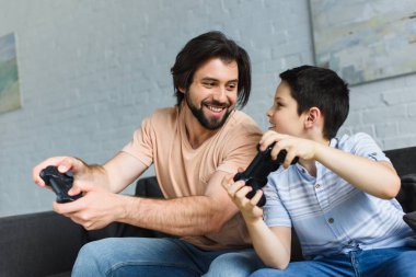 Baba ve oğul birlikte evde video oyunları oynarken gülümseyen portresi