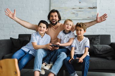 heyecanlı baba ve kanepede oturuyor ve video oyunları birlikte evde oynarken küçük oğulları
