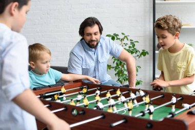 baba birlikte evde masa futbolu oynayan küçük oğulları arıyorsunuz