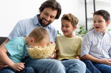 adam ve küçük oğulları film birlikte evde izlerken patlamış mısır yemek gülümseyen