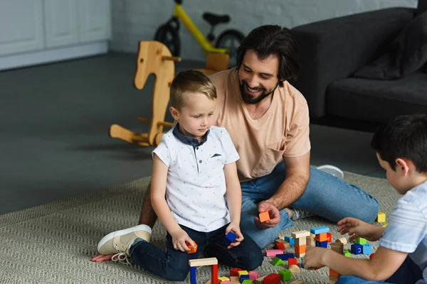 Baba ve ahşap bloklar ile birlikte evde katta oynayan çocuklar