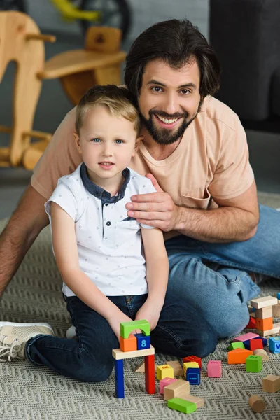Sorrindo Pai Filho Olhando Para Câmera Enquanto Brincava Com Blocos — Fotografia de Stock Grátis