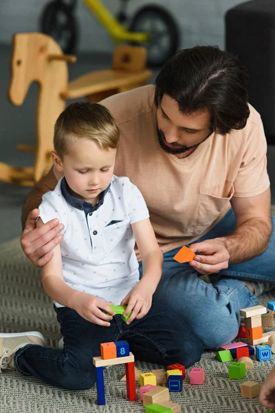 Father Hugging Little Son While Playing Wooden Blocks Together Home — Free Stock Photo