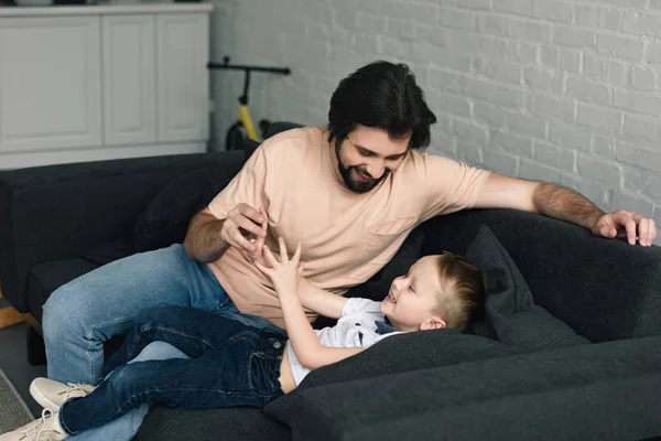 幸せな父と自宅のソファの上の小さな息子の肖像画 — ストック写真