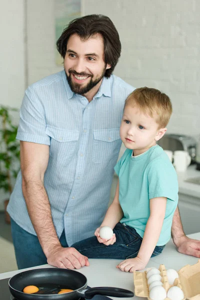 Portrait Smiling Father Little Son Raw Egg Hand Kitchen Home — Free Stock Photo
