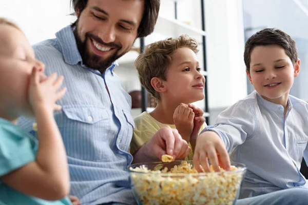 Homem Sorridente Filhos Pequenos Comendo Pipocas Enquanto Assistem Filme Juntos — Fotografia de Stock Grátis