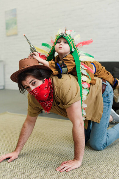 father and little son in costumes playing together at home