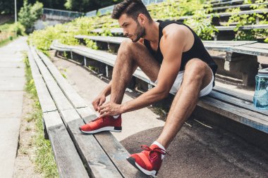 sporcu spor Bahçesi, bankta otururken ayakkabı bağcığı bağlama yan görünüm 
