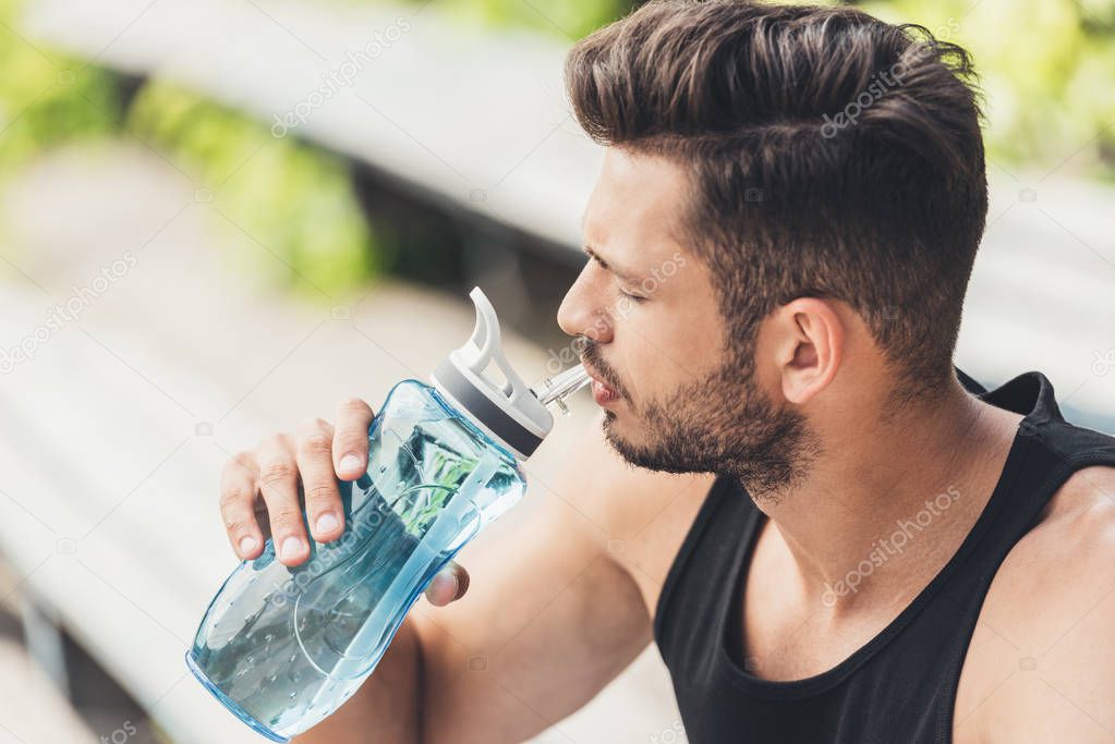 side view of young sportsman drinking water 