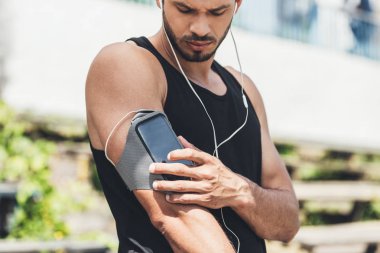 omuz çantası çalıştıran smartphone ile kulaklıklar içinde ciddi genç sporcu 