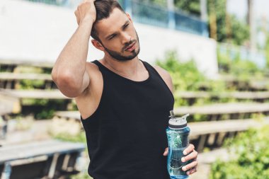 şişe su tutarak genç sporcunun önden görünümü