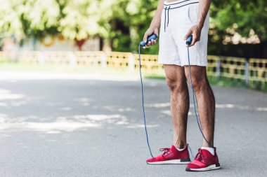 cropped shot of sportive young man with jumping rope clipart