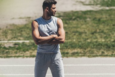 koşu parkuru üzerinde çapraz kolları olan kas genç adam