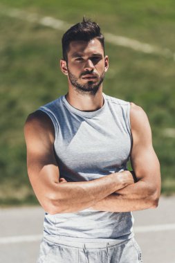 yakışıklı genç adam kameraya çapraz silahlarla seyir spor giyim