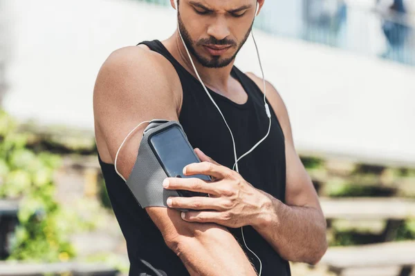 Serio Joven Deportista Auriculares Con Teléfono Inteligente Caso Brazalete Corriendo — Foto de Stock