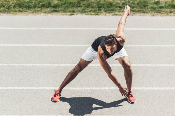 young sportsman exercising on running track at sport playground 