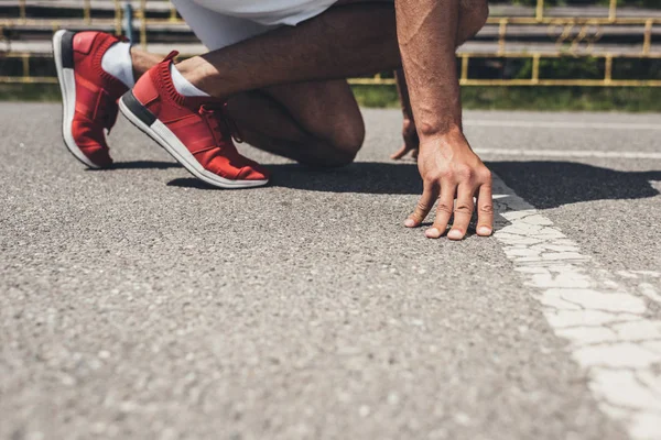 ランニング トラックの開始位置のオスの短距離走者のトリミングされた画像 — ストック写真