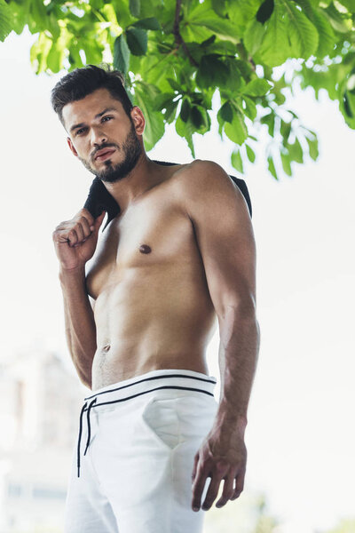 muscular topless sportsman holding towel on shoulder