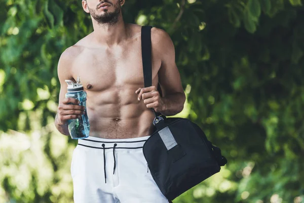 cropped shot of man with bag for sport equipment and fitness bottle