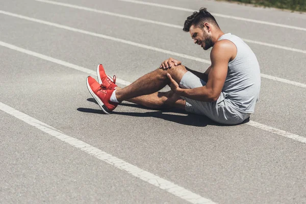 Corredor Joven Con Lesión Pierna Sentado Suelo Pista Atletismo —  Fotos de Stock