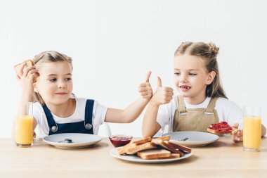 küçük tost reçelli kahvaltı için yeme ve başparmak gösterilmesini beyaz izole kız