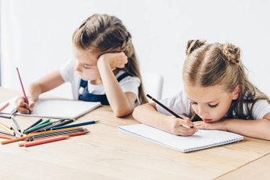 küçük kız öğrenciler üzerinde beyaz izole renkli kalemler albümde birlikte çizim odaklı