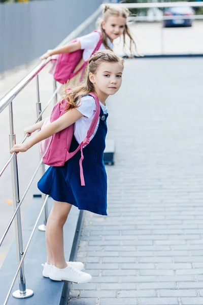 通りで遊ぶピンクのバックパックと小さな女子学生 — ストック写真
