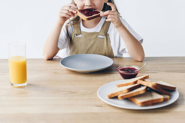 cropped shot of little child eating toast with jam isolated on white