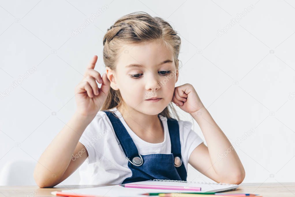 creative little schoolgirl having idea during drawing isolated on white